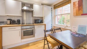 Una cocina moderna con gabinetes blancos, electrodomésticos de acero inoxidable y una mesa de comedor de madera.