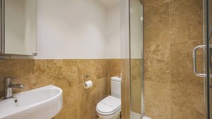 Un baño con lavabo, inodoro y cabina de ducha de vidrio.