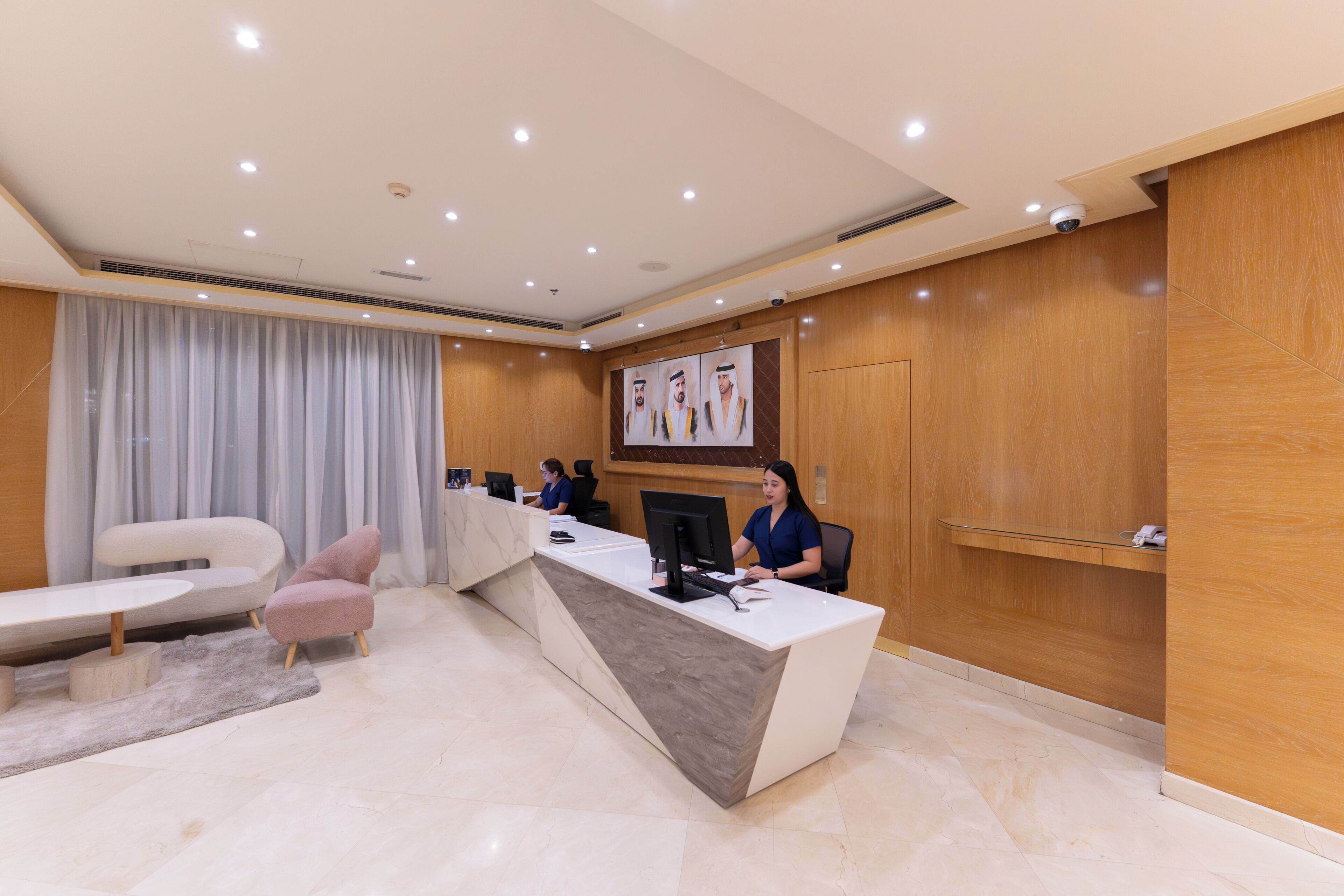 A modern reception area with a marble reception desk, a large window with curtains, and a seating area with a sofa and armchair.
