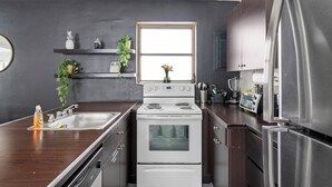 A modern kitchen with a white stove, stainless steel appliances, and wooden countertops. - Brickell Pearl Cozy House/Beach 10 min/Location (Miami)