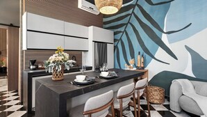 A modern kitchen with a central island, bar stools, and a decorative wall mural. - Villa Mosaico | Stylish & Modern Boutique 1 BR (San Juan)