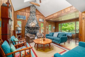 A cozy cabin interior with a stone fireplace, wooden walls, and a blue sofa.