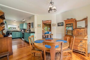 Una cocina con armarios color turquesa, una mesa de comedor de madera con individuales azules y un aparador de madera antiguo con espejo.