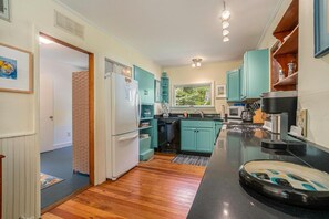 A compact kitchen with teal cabinets, a refrigerator, and a black countertop.