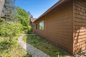 A wooden cabin with a brick exterior, a wooden deck, and a stone chimney.