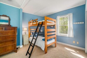 Habitación con literas, cómoda, mesita de noche y ventana con cortinas.