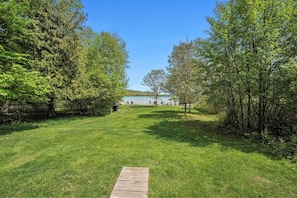 A grassy pathway leading to a lake with trees on either side.