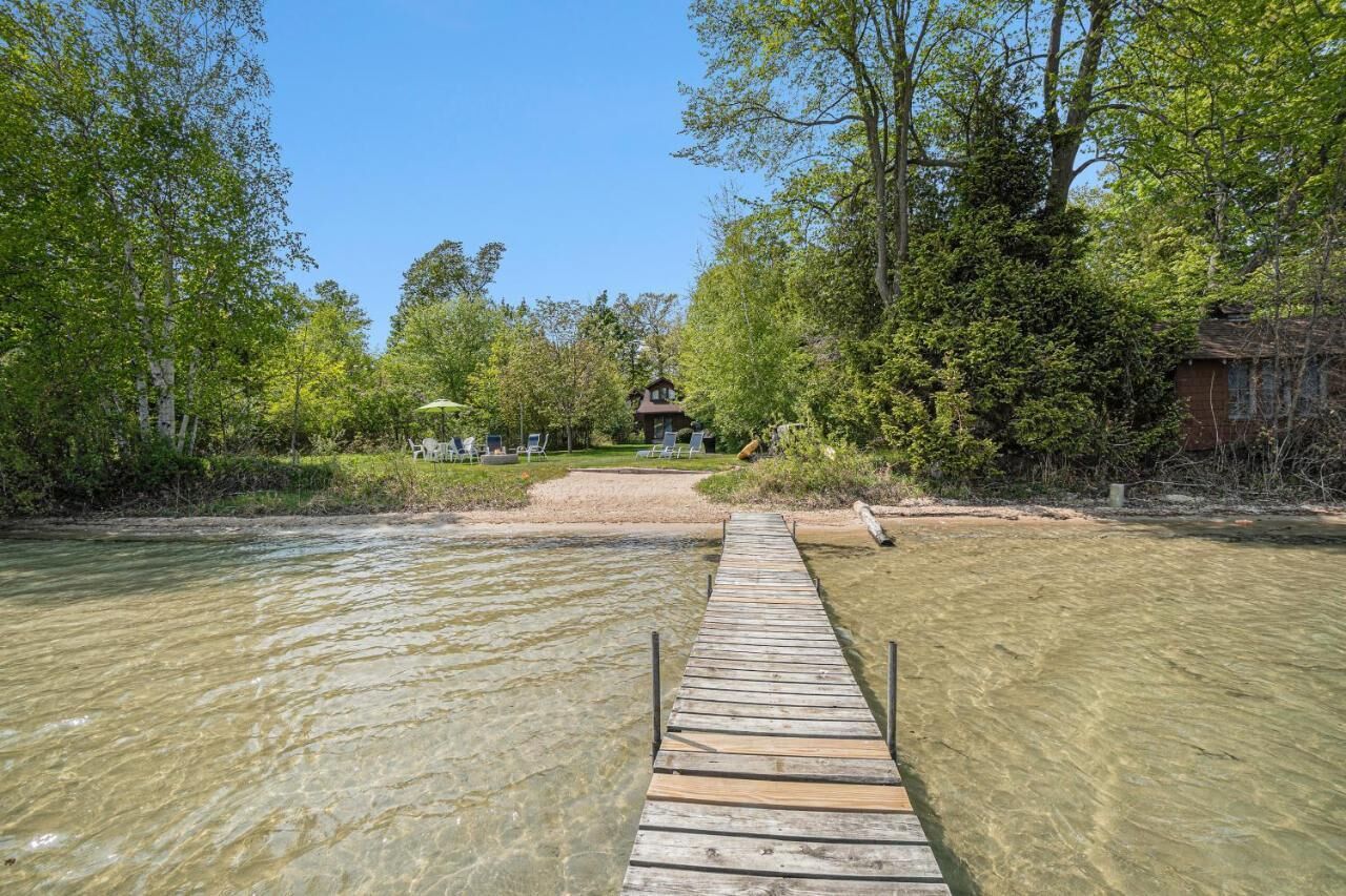Een houten steiger die naar een huis leidt, omringd door bomen.