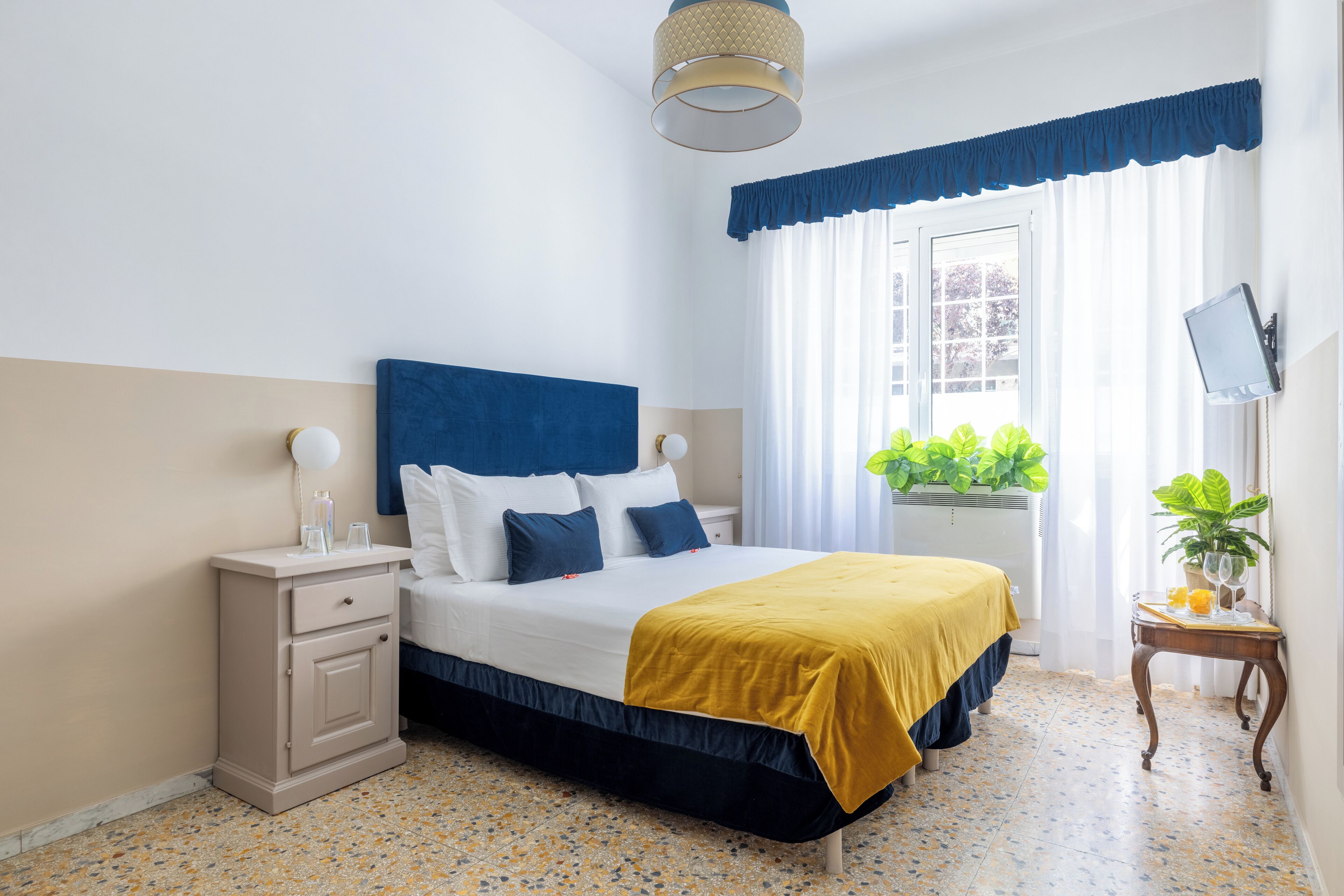Ein ordentlich eingerichtetes Schlafzimmer mit Bett, Nachttisch und einem kleinen Tisch mit Pflanze.