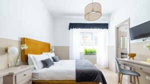 Ein Schlafzimmer mit Bett, Nachttisch, Lampe und einem Fernseher auf einem Schreibtisch.