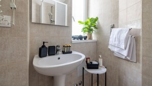 Ein modernes Badezimmer mit Waschbecken, Spiegel und Topfpflanze.