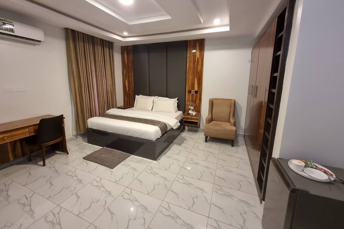 Ein modernes Hotelzimmer mit einem großen Bett, einem Schreibtisch, einem Stuhl und einem Kleiderschrank.