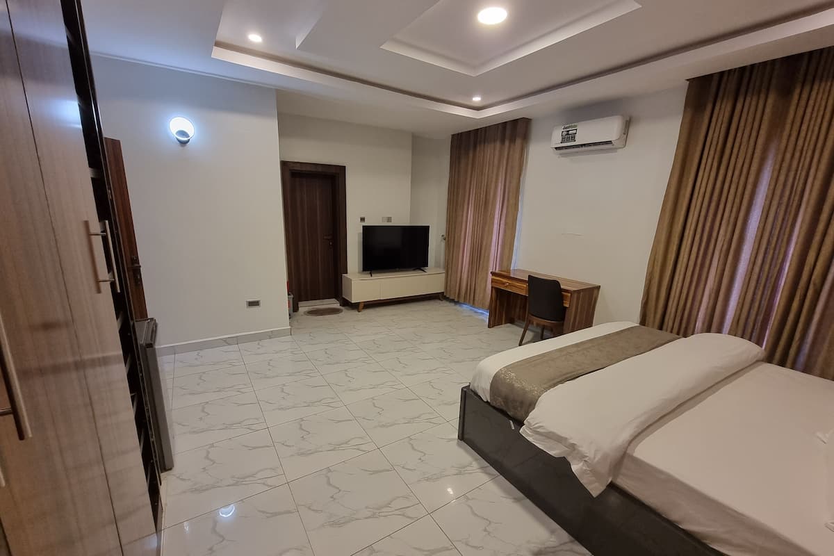 Ein Hotelzimmer mit Bett, Schreibtisch, Fernseher und Klimaanlage.