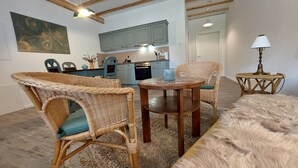 Ein gemütliches Wohnzimmer mit Korbmöbeln, einem runden Holztisch und einem flauschigen Teppich.