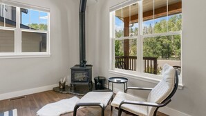 A cozy room with a wood-burning stove, a comfortable chair, and large windows offering a view of the outdoors. - New Build, Pet Friendly, A/C, 5 Minutes to Downtown Durango (Durango)