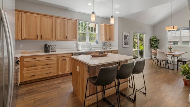 A modern kitchen with wooden cabinets, a central island with bar stools, pendant lighting, and a view to the outdoor patio area. - New Build, Pet Friendly, A/C, 5 Minutes to Downtown Durango (Durango)