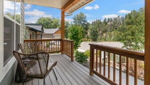 A wooden deck with wicker chairs, a view of a driveway, and surrounding trees. - New Build, Pet Friendly, A/C, 5 Minutes to Downtown Durango (Durango)