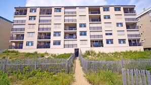 Un immeuble résidentiel à plusieurs étages, doté de balcons, d’une entrée principale et d’une clôture périphérique.