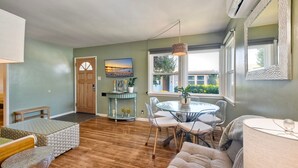 A living room with a wooden floor, a round glass table, and a beige sofa. - Walk 2 Beach, EV Charger, Outdoor Dining, 2 Units (Carlsbad)