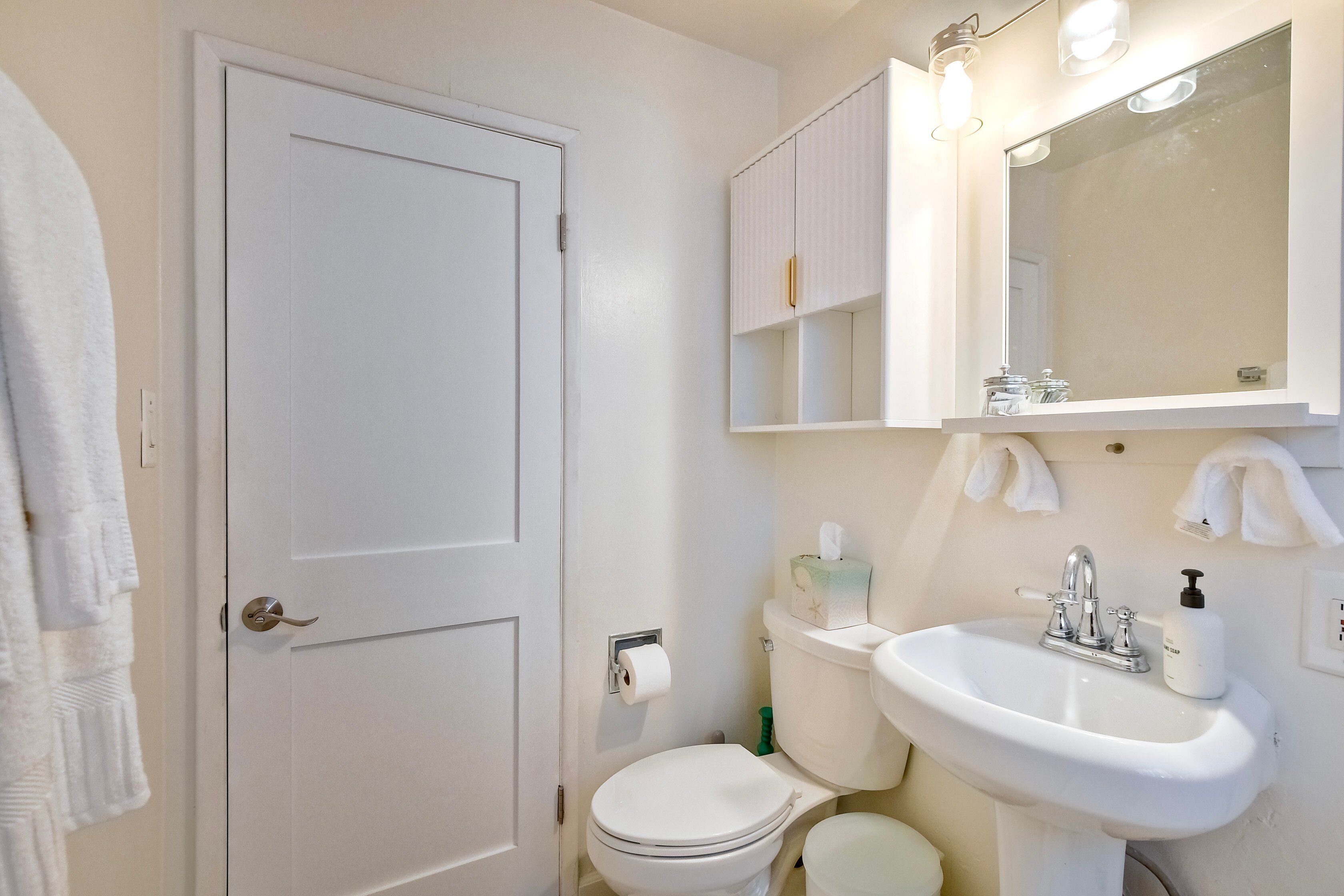 Een badkamer met toilet, wastafel en spiegel.