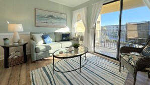 Ein Wohnzimmer mit einer Couch, einem Couchtisch und einem Balkon mit Korbmöbeln.