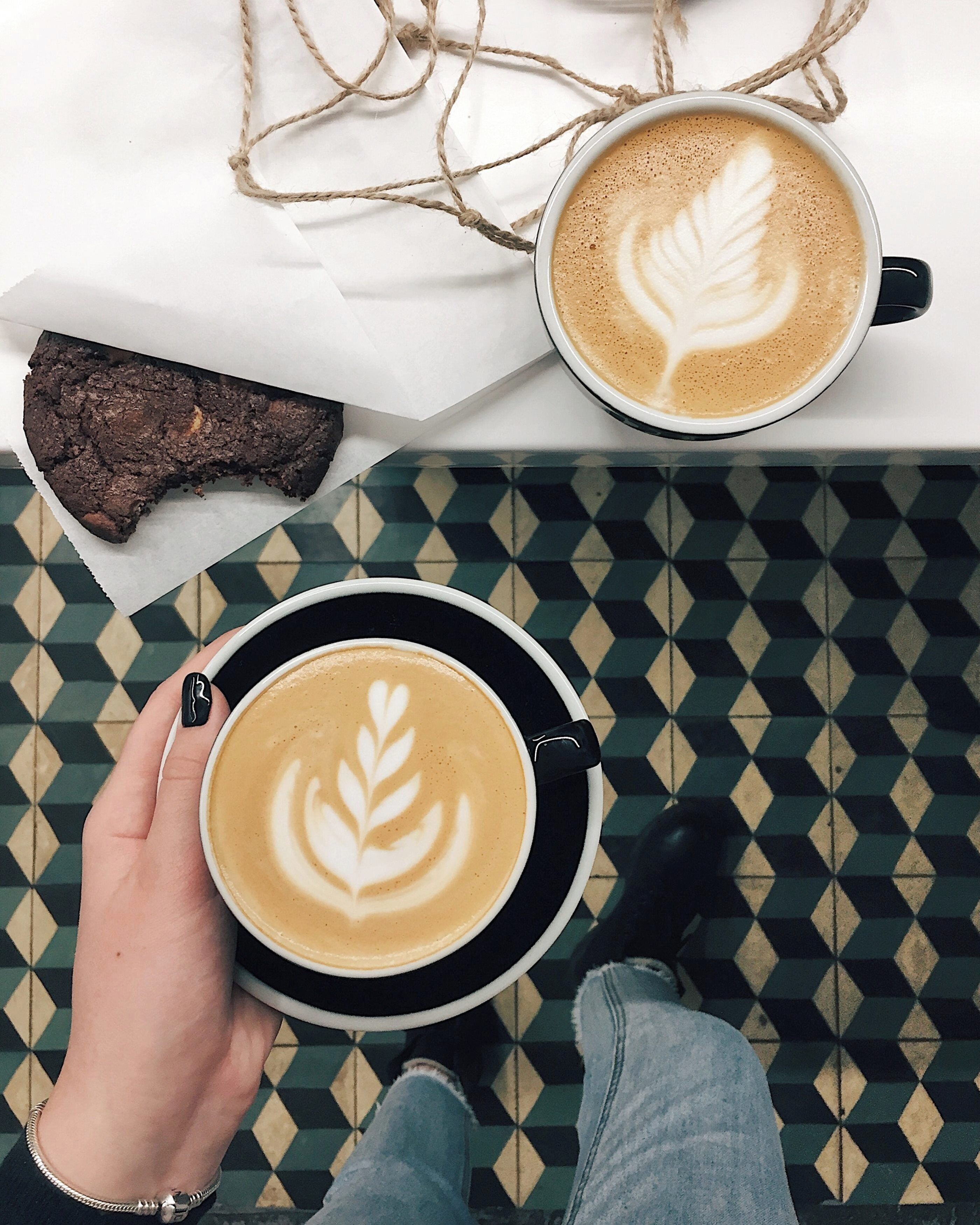 A top-down view of a table with a coffee cup, a chocolate brownie, and a decorative string.