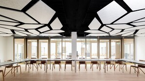 A spacious conference room with a long table, multiple chairs, and a modern ceiling design.