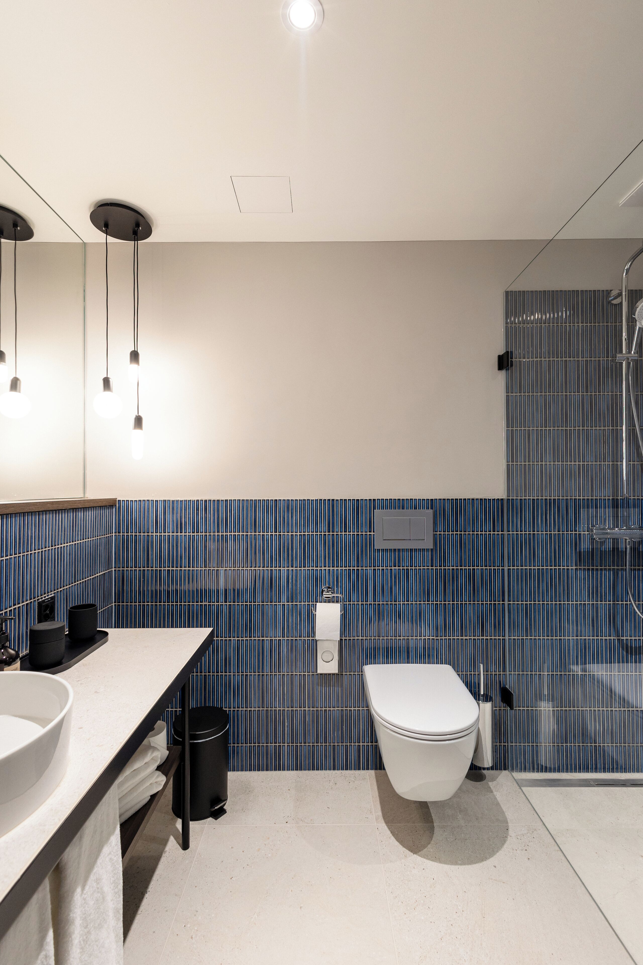 Een moderne badkamer met een grote spiegel, twee wasbakken, een toilet en een douchehoek.