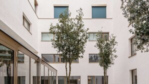 A courtyard with outdoor seating, large planters, and a building with multiple windows.