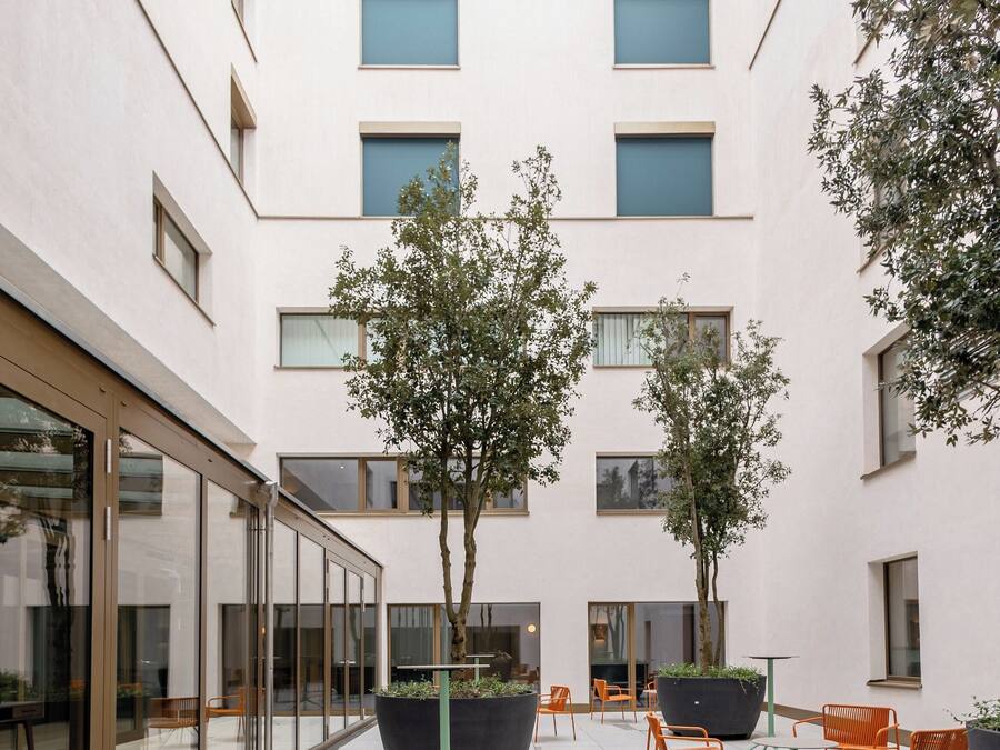 A courtyard with outdoor seating, large planters, and a building with multiple windows.