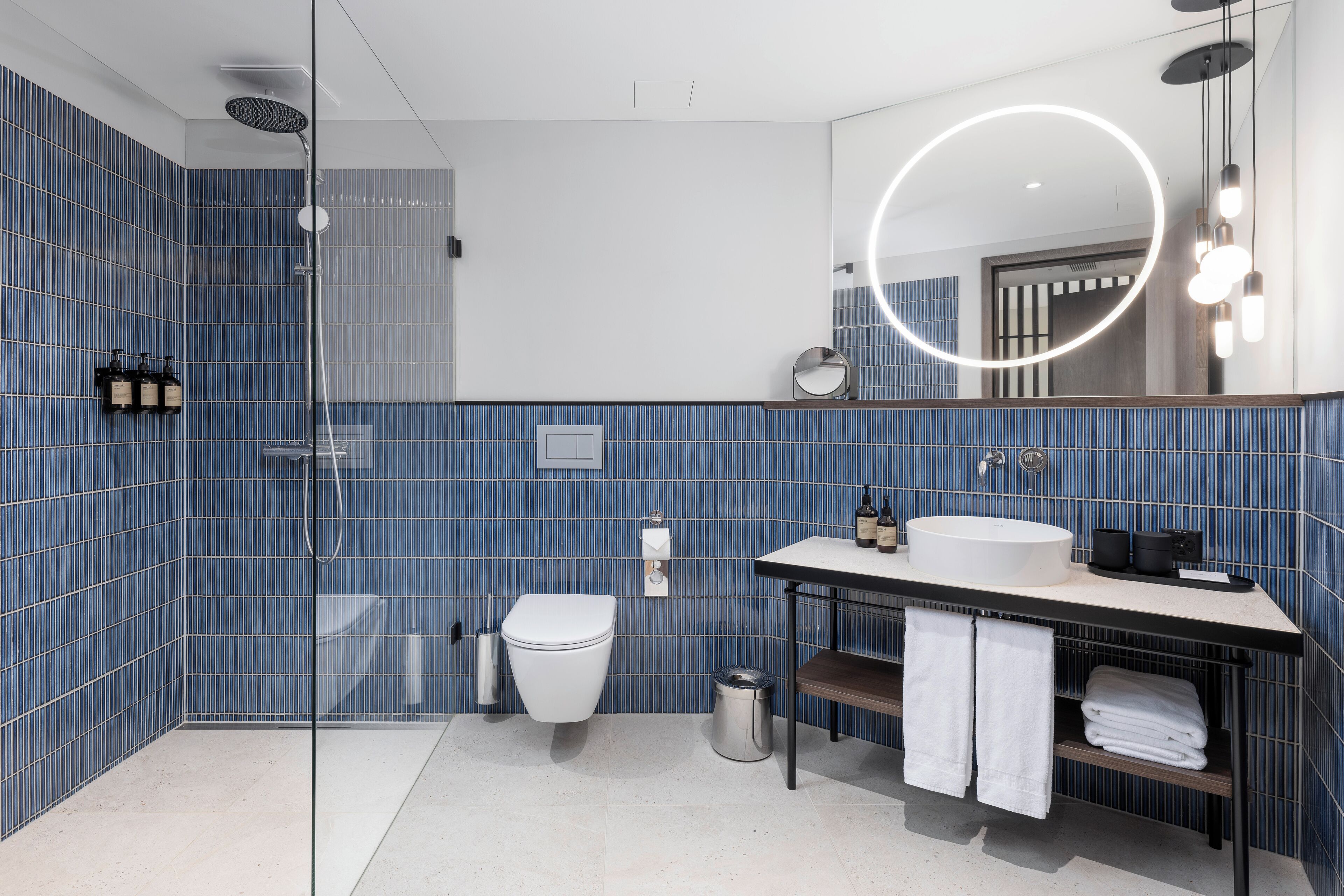 Une salle de bain moderne avec une douche à parois de verre, des toilettes blanches et un meuble-lavabo avec un miroir.