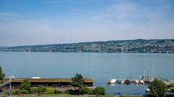 A waterfront view with a dock, boats, and a building with a green roof.