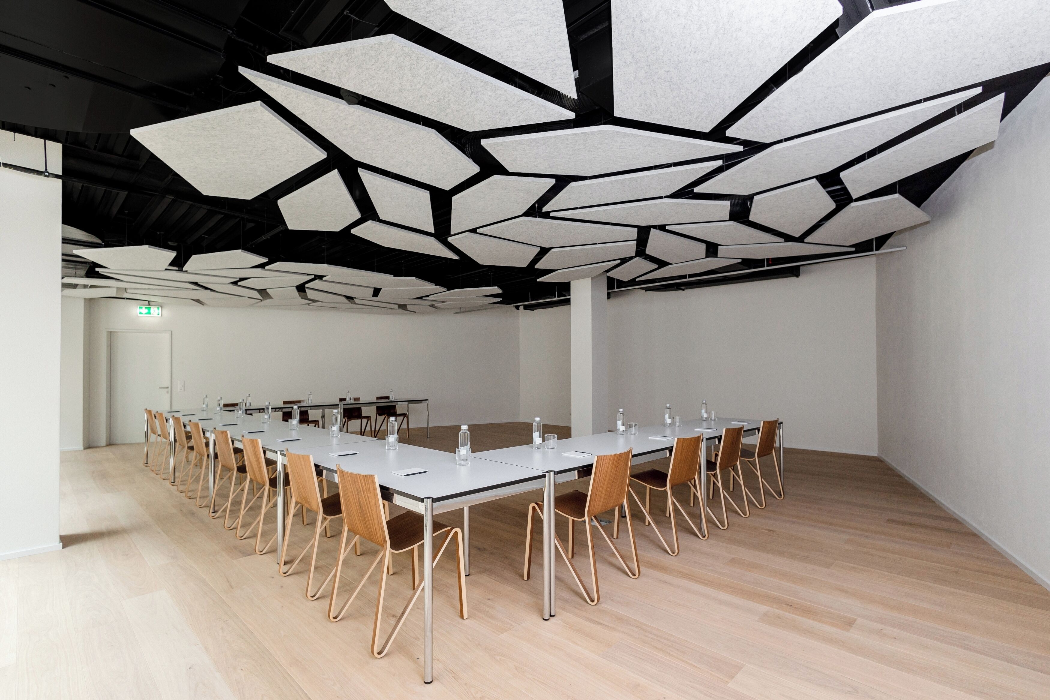 Un salón de conferencias con una larga mesa, sillas y un diseño de techo singular.