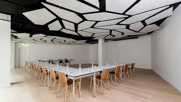 Un salón de conferencias con una larga mesa, sillas y un diseño de techo singular.