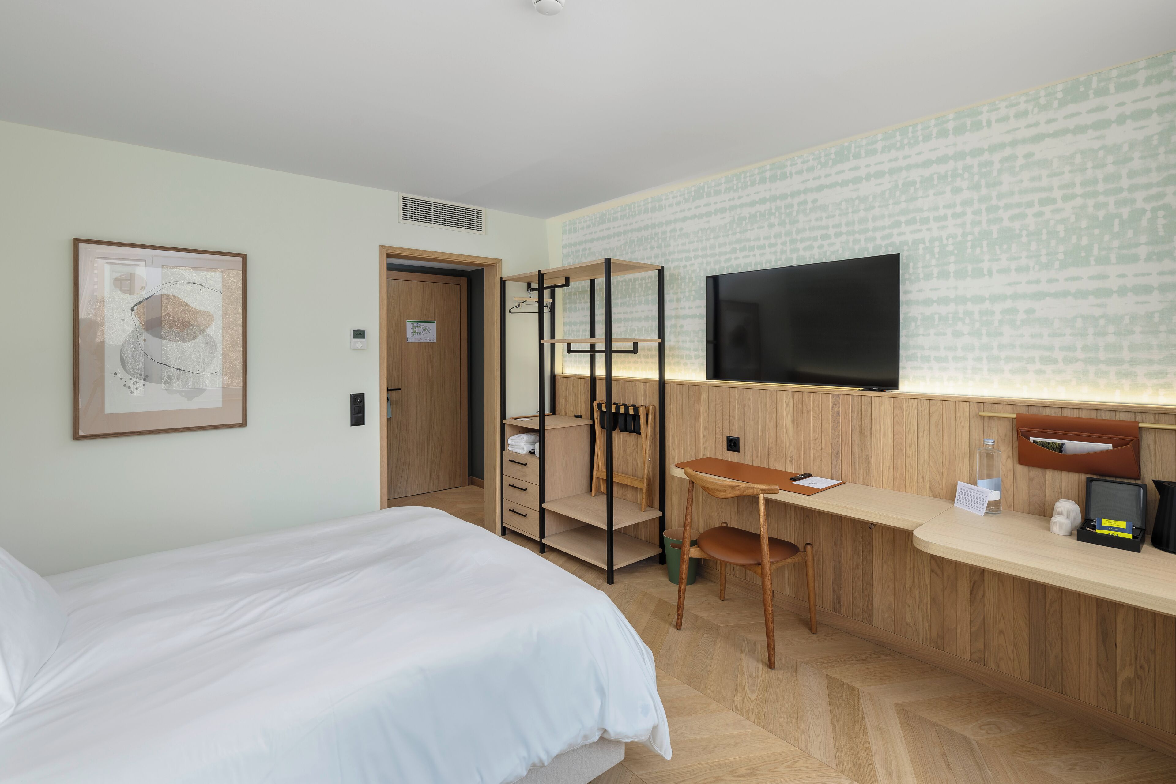 Ein Hotelzimmer mit Bett, Schreibtisch, Fernseher und Kleiderschrank.