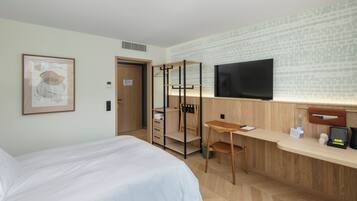 Ein Hotelzimmer mit Bett, Schreibtisch, Fernseher und Kleiderschrank.