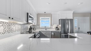 A modern kitchen with white cabinets, a stainless steel refrigerator, and a large island.
