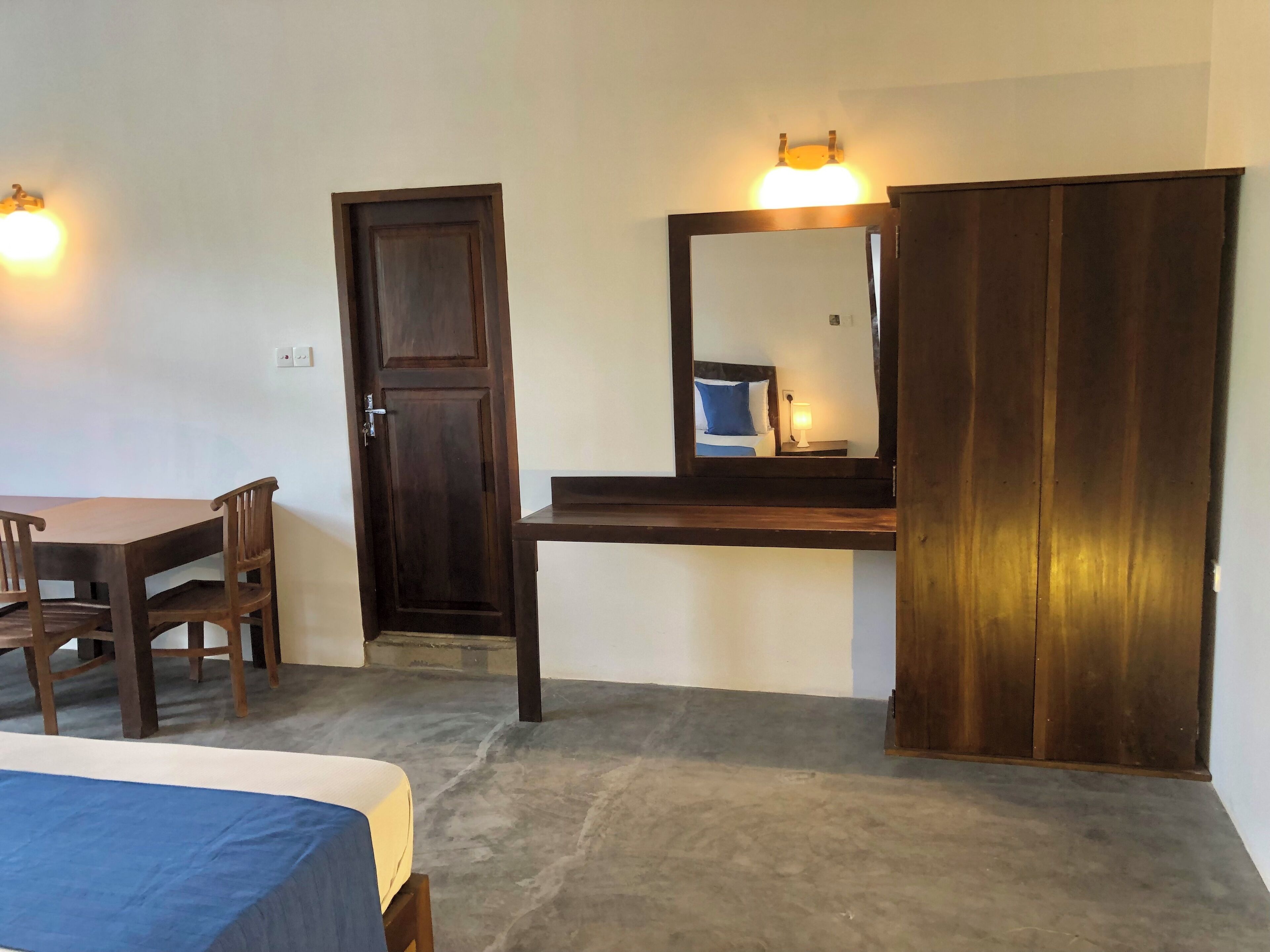 Une pièce comprenant un lit, un bureau, une chaise, une armoire et une porte.