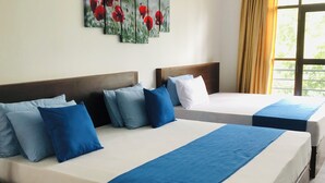 Two beds with blue and white bedding, a painting of red flowers on the wall, and a window with curtains. - Red Letter Hotel (Kandy)