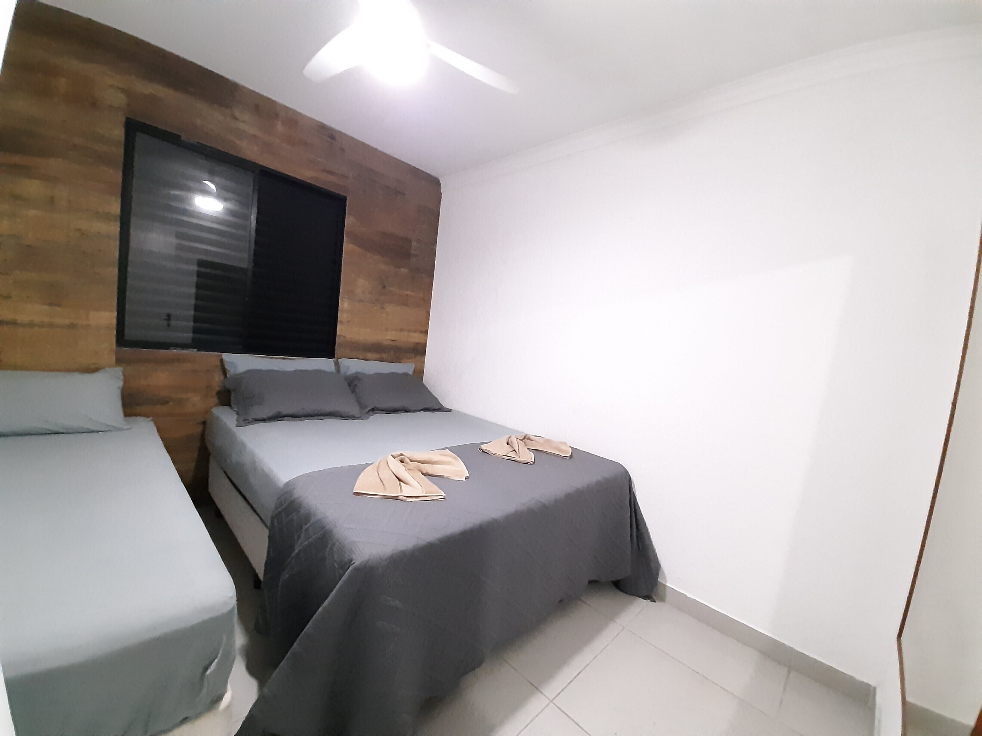 A bedroom with a bed, a small table, and a window.