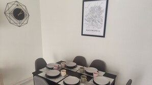 Comedor con una mesa lista para cuatro personas, con platos, tazas y un pequeño adorno.
