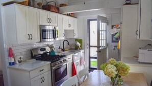 Une cuisine avec des meubles blancs, une cuisinière, un four à micro-ondes et une table à manger avec des chaises.