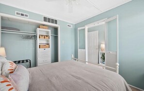 A bedroom with a bed, a closet with shelves, and a door leading to another room. - Updated Mid-Town Ocean Block Unit - Ready for Summer Fun! (Ocean City)