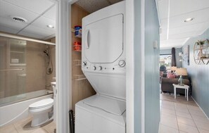 A compact bathroom with a bathtub, toilet, and a white washing machine. - Updated Mid-Town Ocean Block Unit - Ready for Summer Fun! (Ocean City)