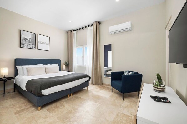 Une chambre d’hôtel moderne équipée d’un lit, d’un bureau, d’une chaise et d’un téléviseur.