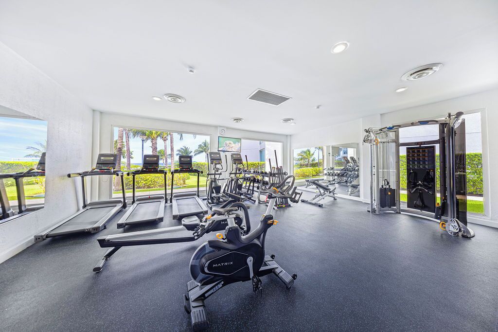 Une salle de sport équipée de tapis de course, de vélos elliptiques et de poids libres.