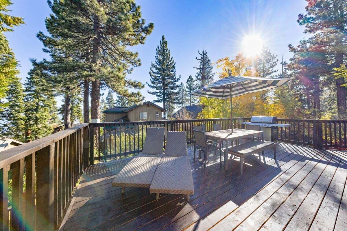 Una terraza de madera con mobiliario exterior, incluyendo un sofá y sillas, además de una parrilla.
