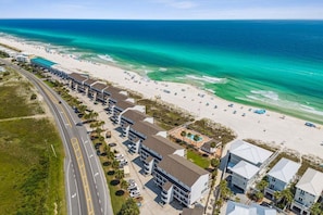 An aerial view of a coastal hotel with multiple buildings, a beach, and a road.
