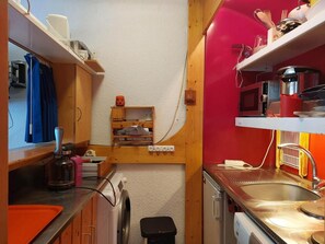A compact kitchen with wooden cabinets, a sink, and a microwave.