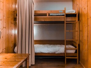 Quarto com beliches, paredes e mesa de madeira.